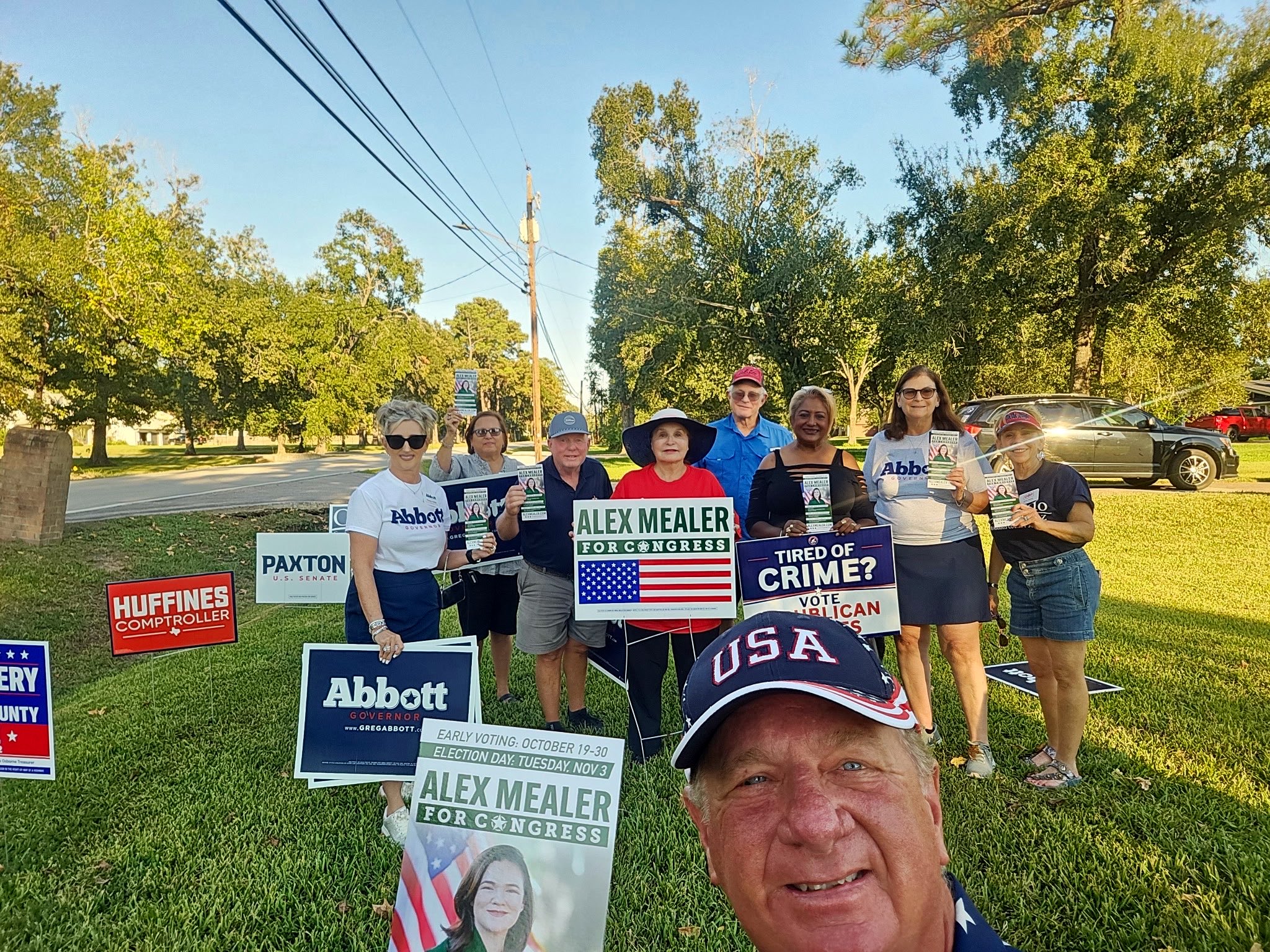 Community volunteers outdoors holding Republican campaign signs and voter information
